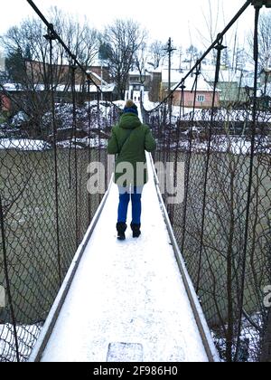 donna che cammina sul ponte sospeso sul fiume Foto Stock