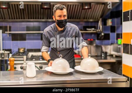 il favoloso chef cuoca con i suoi piatti a base di carne affumicata pronti a servire Foto Stock