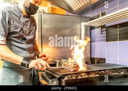 favoloso chef cucina che prepara carne alla griglia Foto Stock