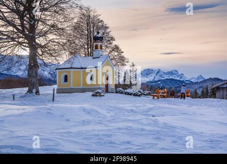 Paesaggio invernale con la cappella di Maria Rast sul Buckelwiesen contro il gruppo Zugspitze (2962m) nei Monti Wetterstein, Krün, Werdenfelser Land, alta Baviera, Baviera, Germania Foto Stock