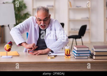 Vecchio insegnante di dentista seduto in classe Foto Stock