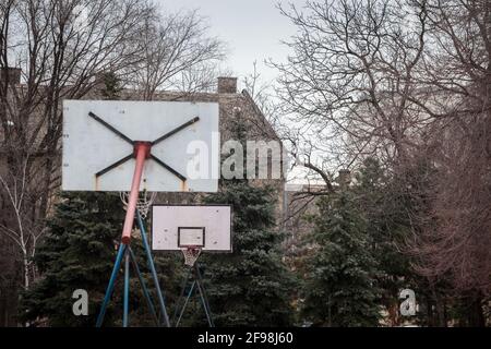 Sfocatura selettiva su un vecchio, decadente danneggiato e marcio basketball backboard, in un decadente parco giochi sportivi, in piedi durante un freddo inverno. Immagine o Foto Stock