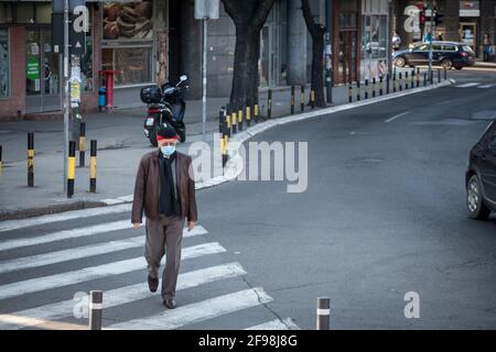 BELGRADO, SERBIA - 21 FEBBRAIO 2021: Anziano che indossa una maschera respiratoria che cammina da solo in una strada di Belgrado, durante il coronav Foto Stock