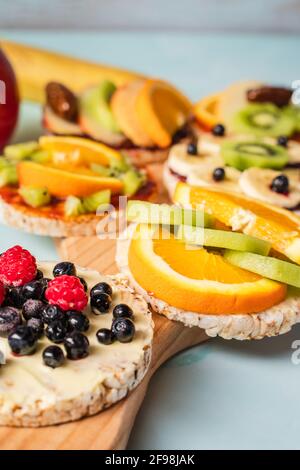 Torte di riso soffinate e croccanti sul tavolo con kiwi di frutta fresca banana mirtilli di mela lamponi e arancio sul tavolo - primo piano su organi sani Foto Stock