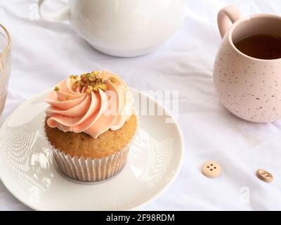 Deliziosa cupcake rosa con tazza rosa su sfondo bianco. Foto Stock