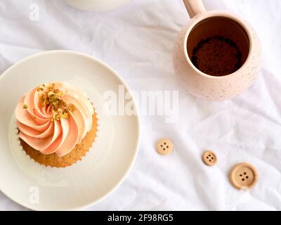 Bella cupcake rosa e tazza rosa in un piatto adagiato su uno sfondo bianco chiaro. Foto Stock