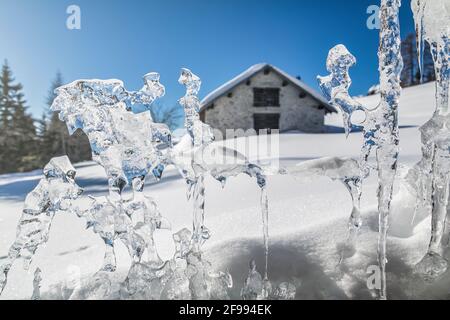 Forme astratte di ghiaccio, sullo sfondo una capanna alpina nelle dolomiti, Passo Duran, Agordino, Belluno, Veneto, Italia Foto Stock