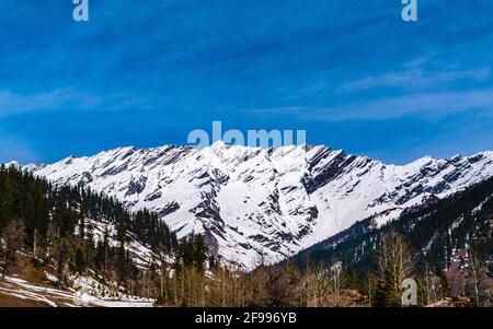 Parapendio alla valle di Solang con le montagne ricoperta di neve di Dhabadhar in background durante il tragitto verso il Passo di Rohtang, Manali, Himachal Pradesh, India. Foto Stock