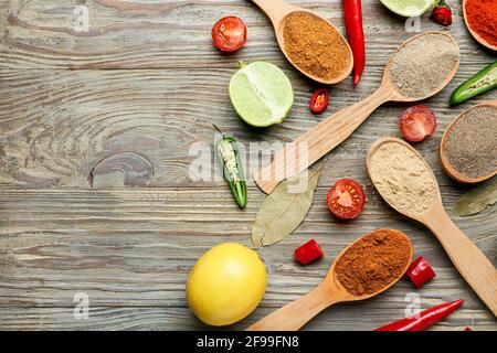 Cucchiai con spezie e verdure diverse su sfondo di legno Foto Stock
