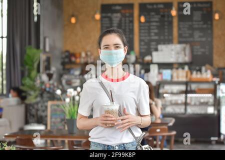 Le donne asiatiche indossano la maschera facciale nel caffè, le donne asiatiche indossano la maschera proteggono il cavid19 del coronavirus Foto Stock