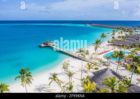 Splendida vista aerea della piscina e della spiaggia del resort con molo in legno. Lussuoso hotel tropicale, piscina, sedie a sdraio, lettini, palme Foto Stock