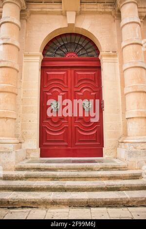 Scalini che conducono alla vibrante porta rossa e a battitori ornamentali in un edificio a Mdina, Malta. Foto Stock