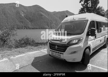 Motorhome / Van 'Vantourer Nero e Bianco' di fronte Spettacolari dintorni di un lago e alcune montagne dal lago como Foto Stock