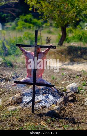 Agnello intero asado, barbecue su croce di ferro spiedo accanto al fuoco aperto in Altea la Vella, Alicante, Spagna Foto Stock