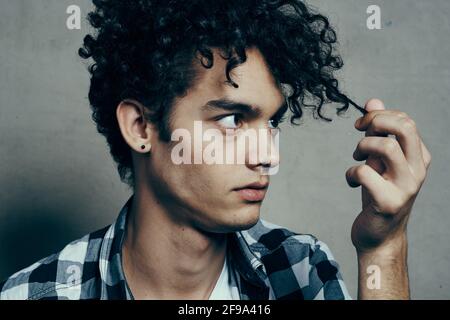 l'uomo esamina i suoi blocchi di capelli e plaid grigio di sfondo camicia modello ragazzo bello Foto Stock