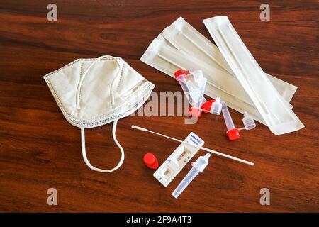 Kit di test automatico per antigene rapido Covid-19 con risultato negativo, tamponi nasali, provette, dispositivo di rilevamento e maschera chirurgica ffp-2 su un tavolo di legno marrone Foto Stock