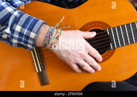 Bracciali di amicizia con motivo indiano sul polso del chitarrista Foto Stock