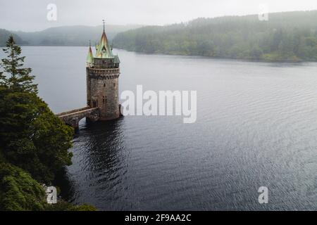 Torre di pietra con un tetto di rame sulle rive di Lago Vyrnwy nella nebbia Foto Stock