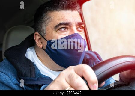Uomo di mezza età con maschera protettiva contro il virus veicolato che guida molto attento e teso nel concetto di salute contro il coronavirus e pandemia con s Foto Stock