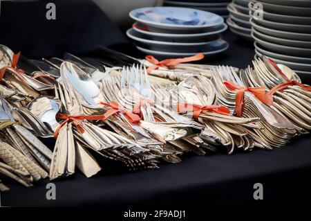 Vecchie posate d'argento vintage legate insieme con nastro rosso per vendita in un mercato antico Foto Stock