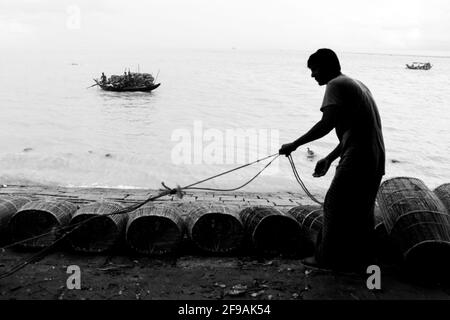 Pescatore in preparazione per la pesca con gabbia e corda sulla riva del fiume ho catturato questa immagine il 15 settembre 2020 da Chandpur, Bangladesh Foto Stock