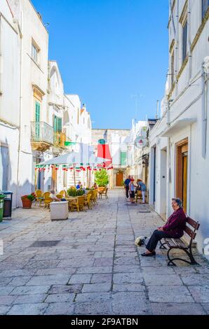 CISTERNINO, ITALIA, 21 GIUGNO 2014: La gente sta godendo una giornata di sole su un vicolo nella città italiana di Cisternino Foto Stock