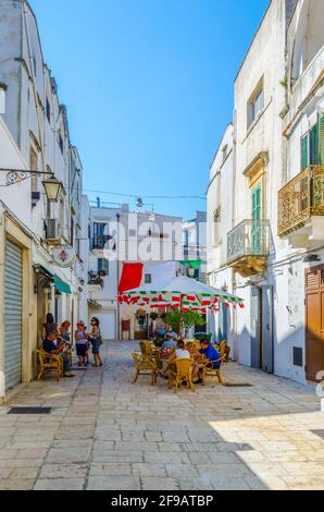 CISTERNINO, ITALIA, 21 GIUGNO 2014: La gente sta godendo una giornata di sole su un vicolo nella città italiana di Cisternino Foto Stock