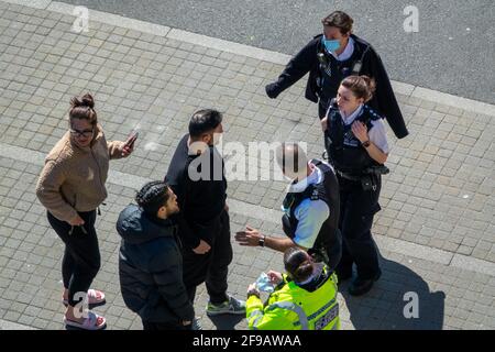 Gli ufficiali di polizia discutono con due maschi asiatici nel mezzo della strada. Foto Stock