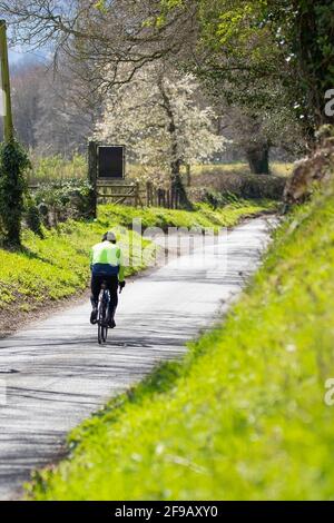 Un ciclista da solo in bicicletta su una vuota strada di campagna inglese Foto Stock