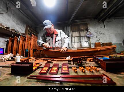 (210417) -- HANGZHOU, 17 aprile 2021 (Xinhua) -- Han Minghua fa un modello della barca rossa al laboratorio di Jiaxing Minghua Ship Model Manufacturing Co., Ltd. A Yuxin Città di Jiaxing City, Provincia di Zhejiang della Cina orientale, 13 aprile 2021. Sul lago Nanhu a Zhejiang riposa una delle barche più famose del paese -- la barca rossa. Ogni giorno, molti visitatori si accodano per rendere omaggio alla storica barca, che onora la conclusione del primo Congresso Nazionale del Partito Comunista Cinese (CPC) nel 1921. In occasione del centesimo anniversario del CPC, Han Minghua, ereditatore del modello Red Boat Foto Stock