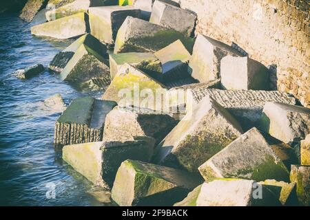 Primo piano delle rocce sporche giganti coperte di muschio L'acqua sul lato del ponte Kursaal Foto Stock