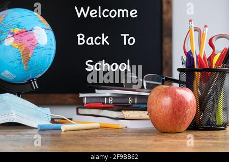 Scrivania della scuola con testo Welcome Back to School scritto sulla lavagna in background Foto Stock