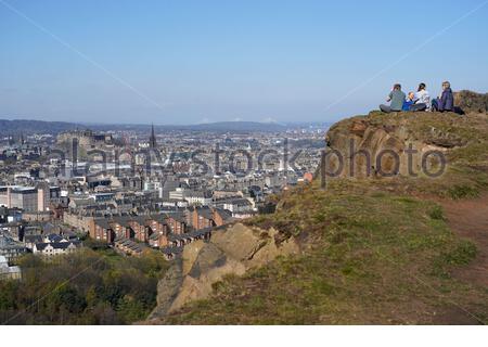 Edimburgo, Scozia, Regno Unito. 17 Aprile 2021. Il primo fine settimana completo di limitazioni di viaggio in tutta la Scozia, le persone si affollano nei soliti punti di interesse per i visitatori per godersi il sole e la vita all'aperto a Holyrood Park. Vista sui tetti della città fino al castello di Edimburgo da Salisbury Crags. Credit: Craig Brown/Alamy Live News Foto Stock