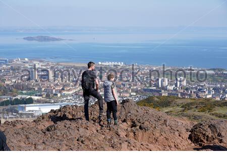 Edimburgo, Scozia, Regno Unito. 17 Aprile 2021. Il primo fine settimana completo di limitazioni di viaggio in tutta la Scozia, le persone si affollano nei soliti punti di interesse per i visitatori per godersi il sole e la vita all'aperto a Holyrood Park. Ammira la vista sul Forth Estuary e sull'isola di Inchkeith dalla cima di Arthurs Seat. Credit: Craig Brown/Alamy Live News Foto Stock