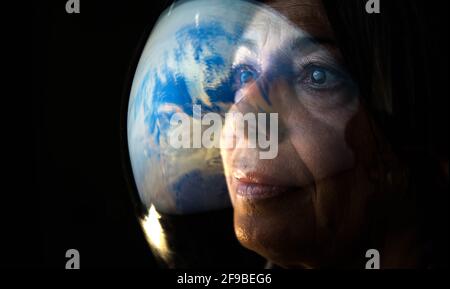 Ritratto dell'astronauta femminile adulta che guarda il pianeta terra - viaggio spaziale, esplorazione e concetto di colonizzazione del sistema solare. Foto Stock