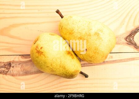 Due pere biologiche giallo chiaro, mature, succose, dolci, primo piano, su un tavolo di legno. Foto Stock