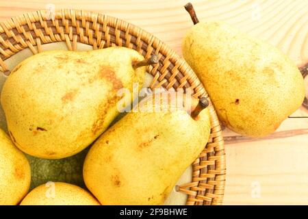 Diverse pere succose in un piatto di ceramica, primo piano, su un tavolo di legno. Foto Stock