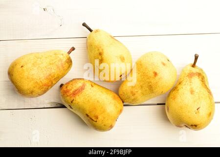 Cinque pere mature gialle su un tavolo di legno dipinto. Foto Stock