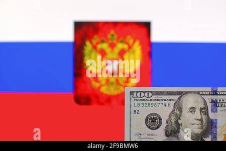 Banconote da 100 dollari USA primo piano su sfondo sfocato di Bandiera della Federazione Russa e stemma Foto Stock