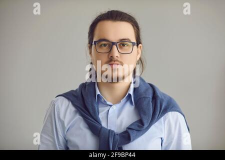Ritratto in studio di un giovane intelligente serio in ufficio camicia e occhiali Foto Stock