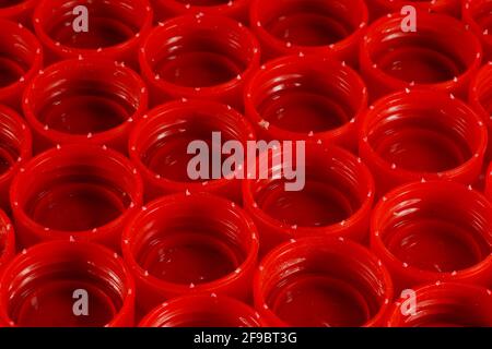 Tappi rossi in flaconi in HDPE (polietilene ad alta densità) separati in base ai colori preparati per il riciclaggio. Materiali riciclabili. Foto Stock