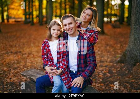 foto di una meravigliosa famiglia nella foresta d'autunno una panca Foto Stock