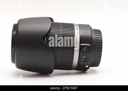 Obiettivo zoom nero di grandi dimensioni per fotocamere reflex digitali con paraluce obiettivo sdraiato su sfondo bianco Foto Stock