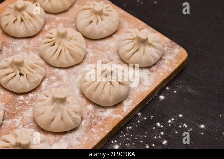 File dritte di khinkali georgiani non cotti da una tavola di legno sdraiato all'angolo Foto Stock