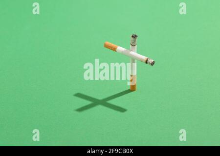 Il fumo uccide il concetto con le sigarette come una croce grave con l'ombra di croce sul prato verde del cimitero. Foto Stock