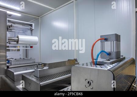Lavorazione del confezionamento di burro e formaggio su confezionatrice sottovuoto per alimenti in fabbrica industriale alimentare. Confezionamento di burro e formaggio alimentare in pr Foto Stock