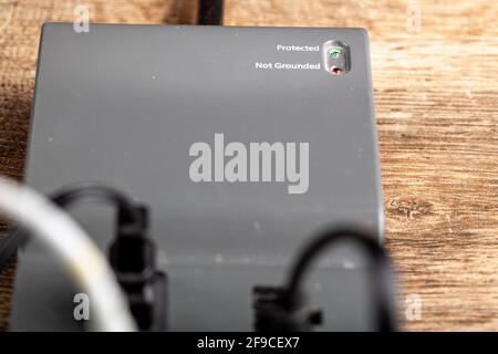 Primo piano vista dall'alto di una basetta di alimentazione a filo con protezione da sovratensioni. Più dispositivi elettronici sensibili sono collegati a prese singole e Th Foto Stock