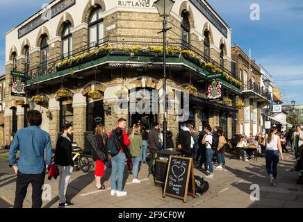 Londra, Regno Unito. 17 Apr 2021. I londinesi navigano e bevono presso l'Upper Mall, Hammersmith, affacciato sul Tamigi. Sole di primavera e un rilassante blocco COVID-19 portano i marinai ai club di vela lungo il Tamigi a Hammersmith e i bevitori alle molte case pubbliche lungo l'Upper Mall. La marea è alta e le case galleggianti risplendono nel sole del pomeriggio. Credit: Peter Hogan/Alamy Live News Foto Stock