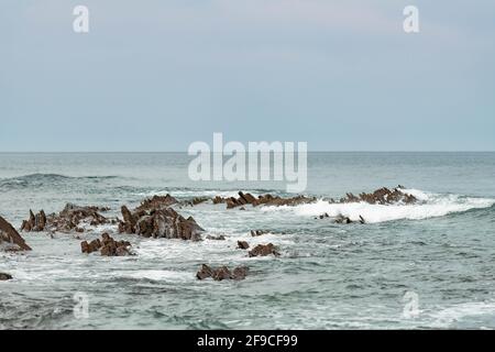 Sakoneta spiaggia nel nord della Spagna piena di rocce affilate emergenti dal fondo dell'oceano Foto Stock