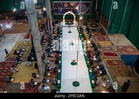 Srinagar, India. 17 Apr 2021. I musulmani del Kashmiri recitano il libro santo islamico Corano durante la recita congregazionale del Santo Corano il 4° giorno del Ramadan in un Imam Badah a Srinagar.il mese più sacro dell'Islam, Ramadan, è un periodo di intensa preghiera, digiuno da alba a tramonto e feste notturne. Khatam al-Quran è una cerimonia normalmente tenuta dai musulmani verso la fine del Ramadan. L'osservanza segna il completamento della lettura dei 30 capitoli (Juzuk) dell'al-Quran. Credit: SOPA Images Limited/Alamy Live News Foto Stock